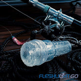 A clear, cylindrical device is shown resting on coiled ropes next to a fishing reel. The Fleshlight GO Torque Portable Stroker Toy features an intricate inner structure and is branded with "Fleshlight GO" in blue text at the bottom right corner of the image, making it the perfect travel buddy for portable convenience.